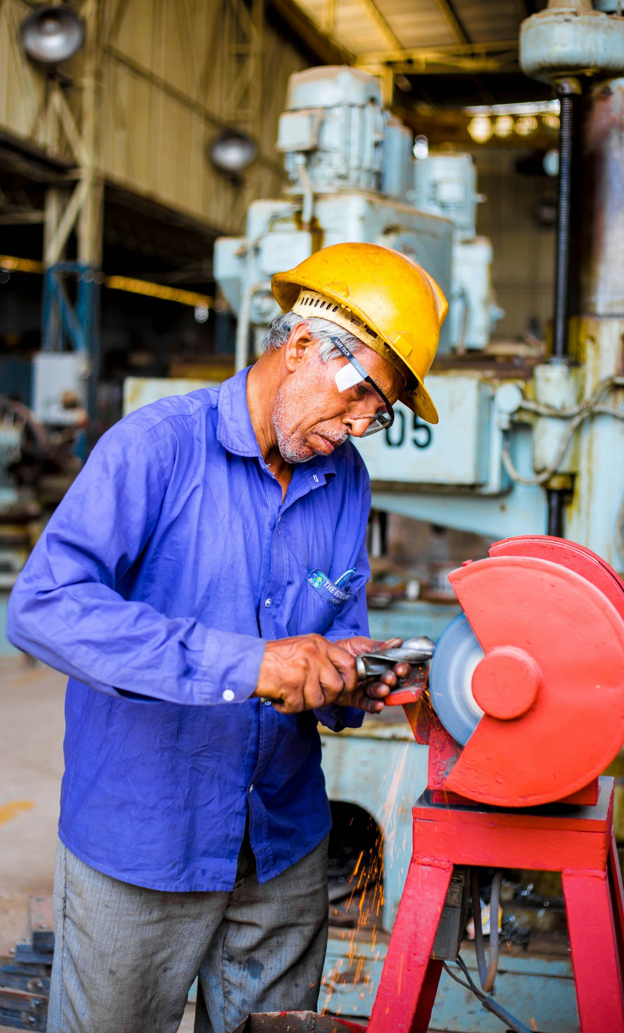 An industrial worker grinding metal inside a workshop