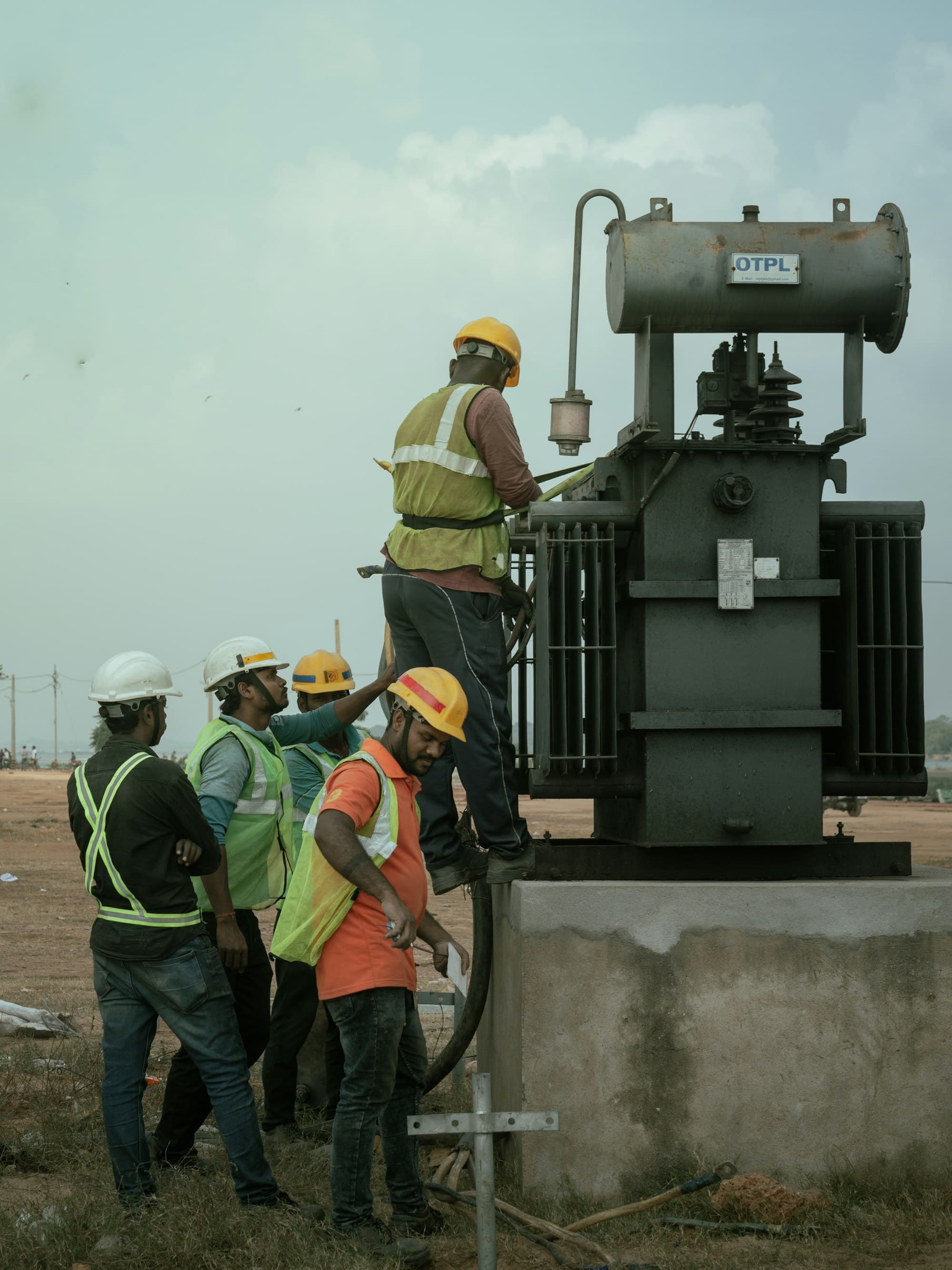 Engineers in hard hats working beside an electrical transformer
