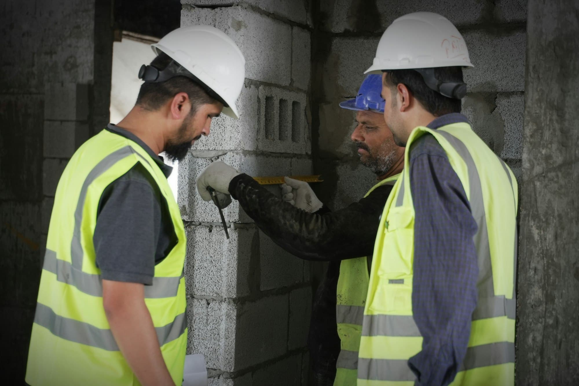 Two workers in safety vests and hard hats inspecting a site